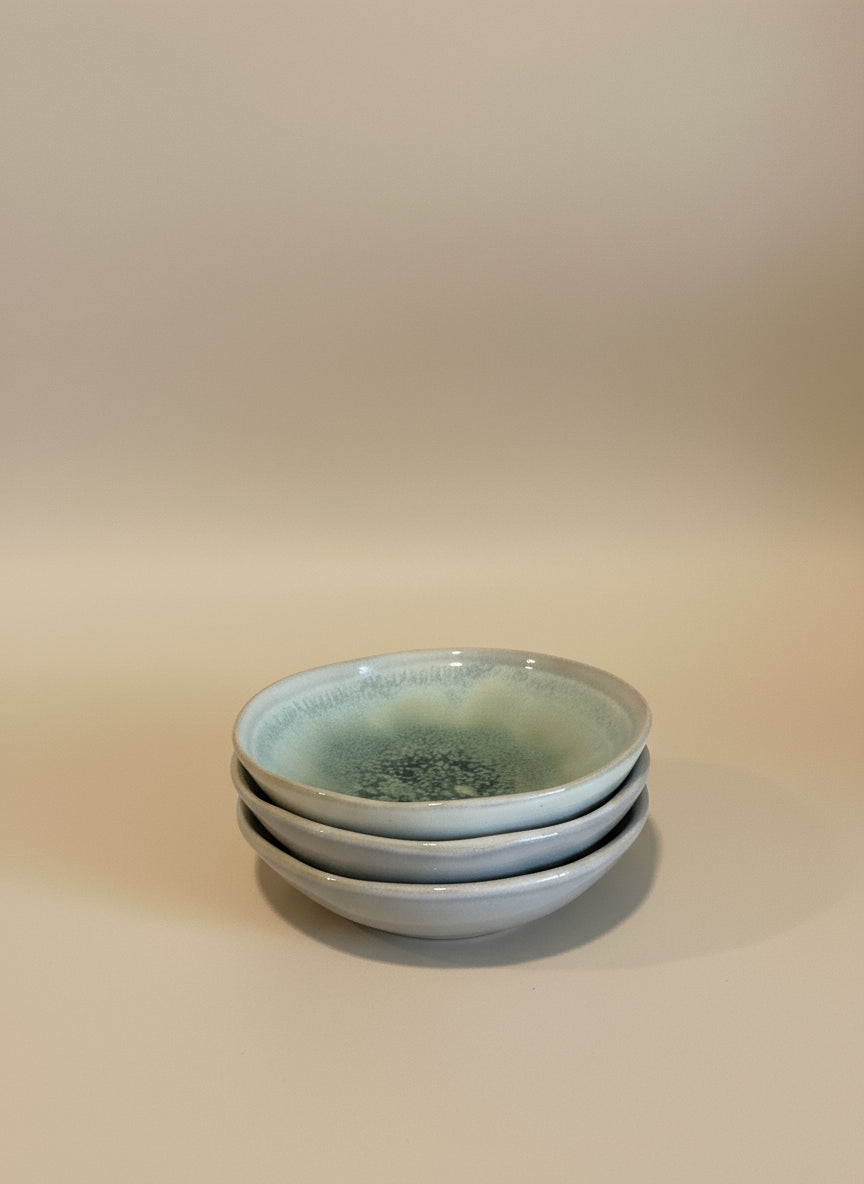 Two ceramic plates stacked on a wooden surface with a white wall background
